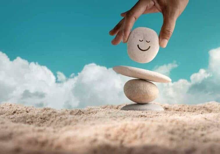 enjoying life concept harmony positive mind hand setting natural pebble stone with smiling face cartoon balance beach sand balancing body mind soul spirit mental health practice