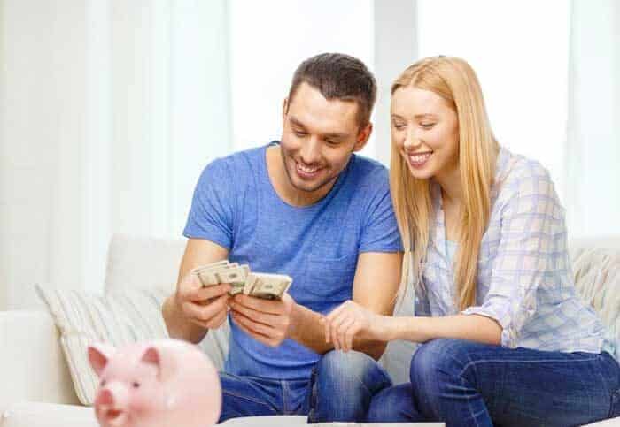 love family finance money happiness concpet smiling couple counting money with piggybank ot table home