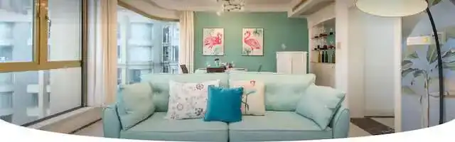 Bright and airy living room with large windows, pastel decor, and comfortable seating.