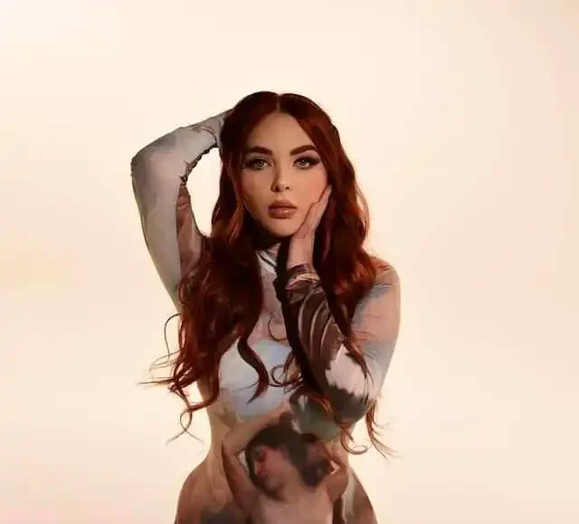 Glamorous woman with long red hair and striking makeup posing elegantly.