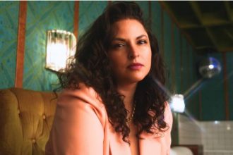 Americana singer-songwriter Danni Nicholls in a peach blazer against teal wallpaper, Nashville 2026.