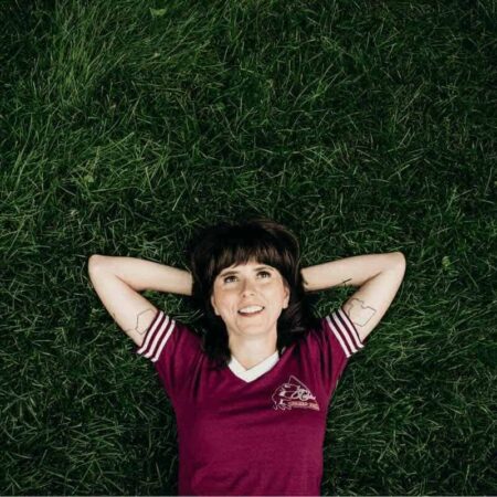 Ellie Heath – Pushing Forty (New Single & Album Announcement) Ellie Heath lying on grass with arms behind head, smiling.
