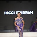 Elegant model in purple evening gown walking on runway during fashion show.