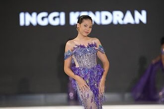 Elegant model in purple evening gown walking on runway during fashion show.