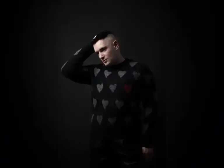 Andrew Spice – Pretty Demons (Remastered 2026) Portrait of Andrew Spice wearing a heart-patterned sweater against a dark background.