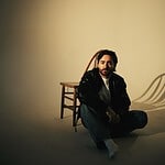 Ike Dweck seated on a chair with a neutral background, promoting his new single and US tour 2026.