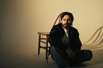 Ike Dweck seated on a chair with a neutral background, promoting his new single and US tour 2026.
