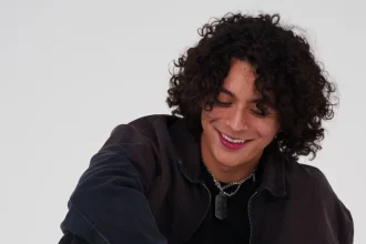 Frankie with curly hair smiling, celebrating new single "R0LL3RC0AST3R".