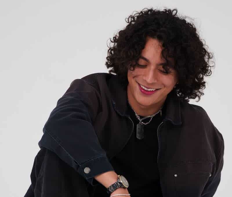 Frankie with curly hair smiling, celebrating new single "R0LL3RC0AST3R".