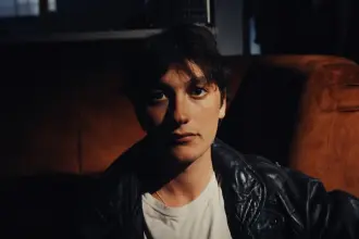 Portrait of YONAH, indie-rock artist, in a dark setting with leather jacket.